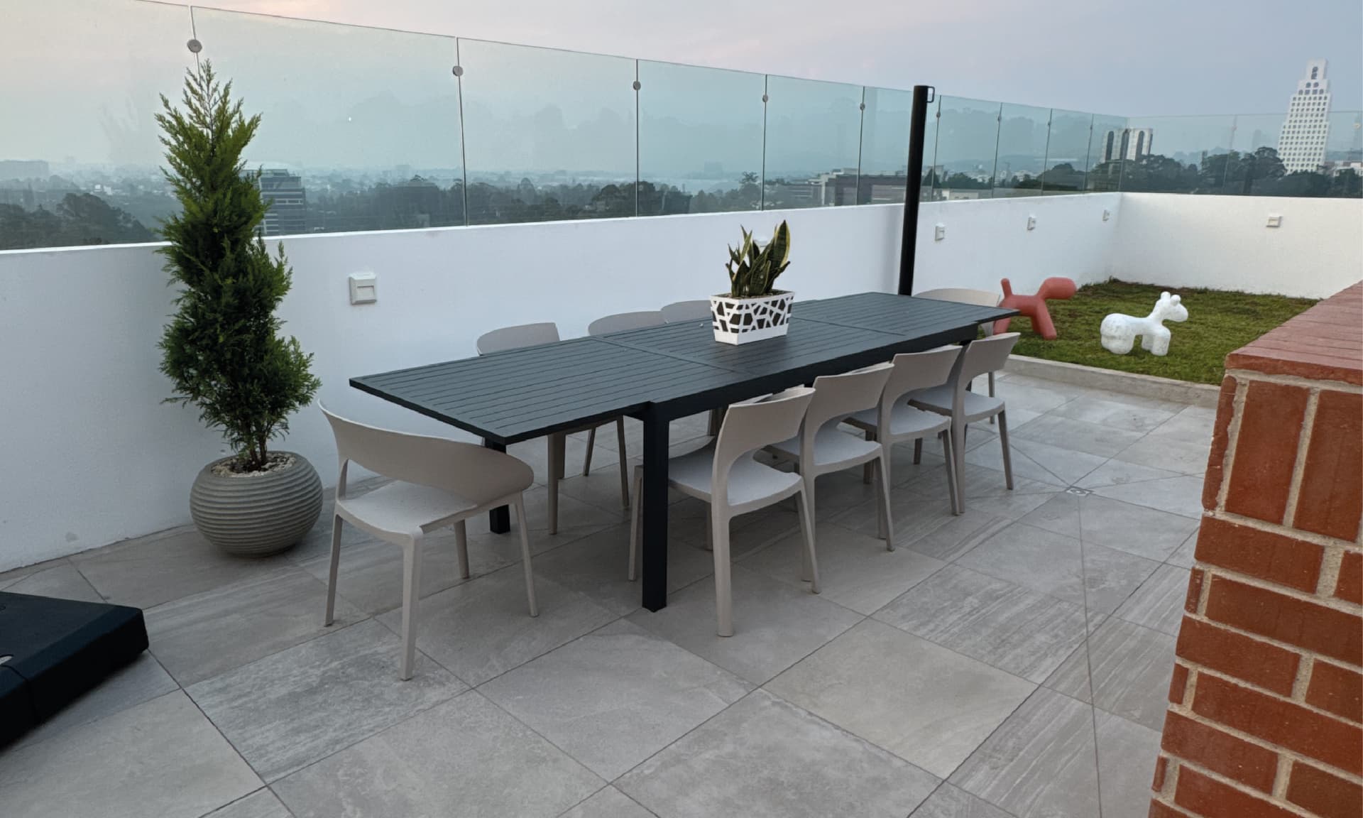 Mesa de comedor exterior en el rooftop de PRIVE con área de barbacoa